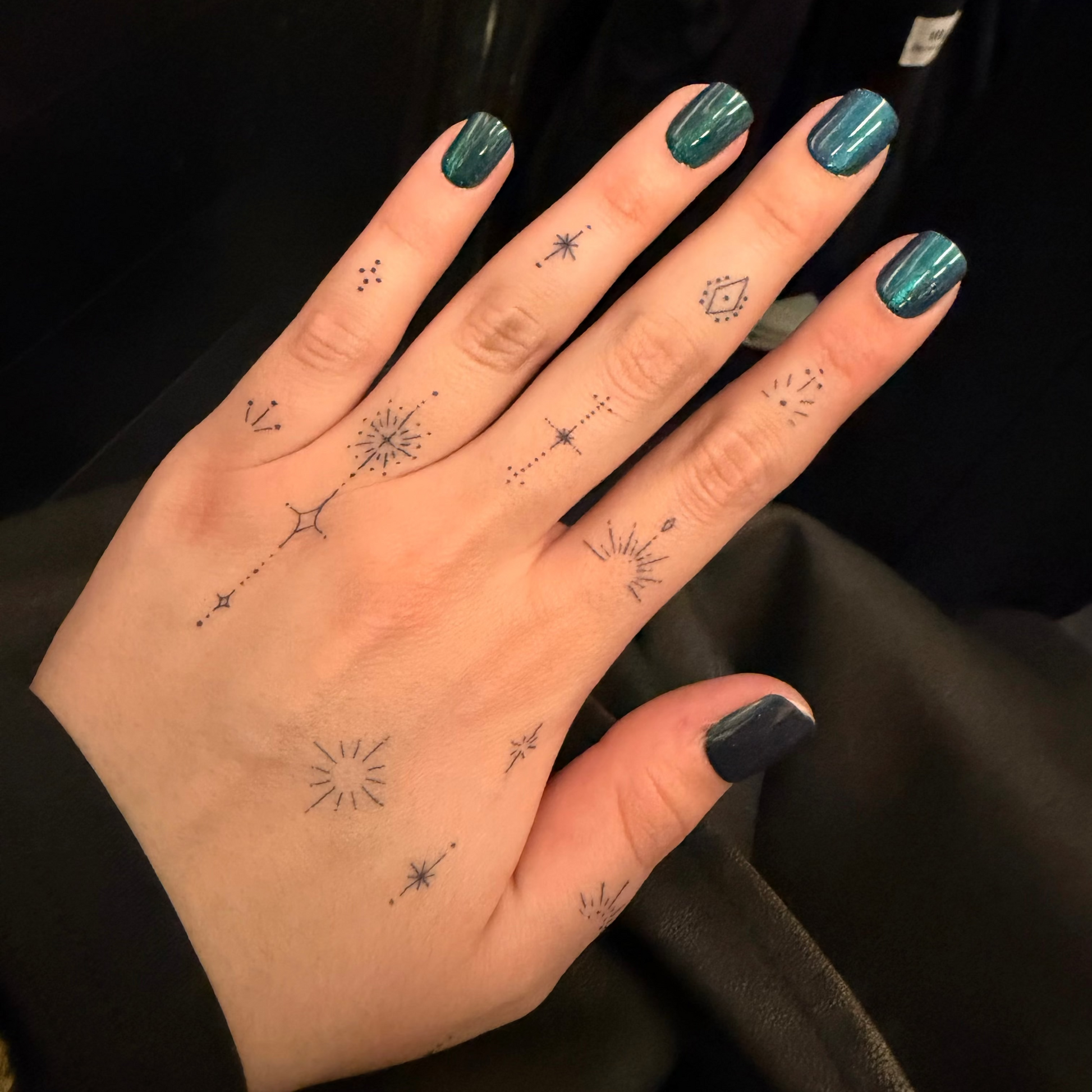 Hand with star-shaped tattoos on a black background